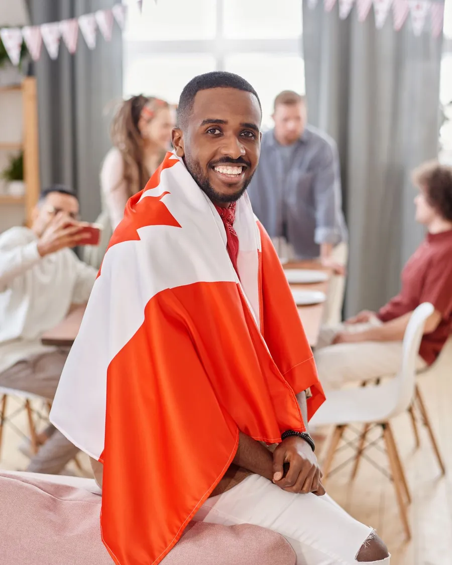 Smiling African man wrapped in a Canadian flag at a Canada Day celebration