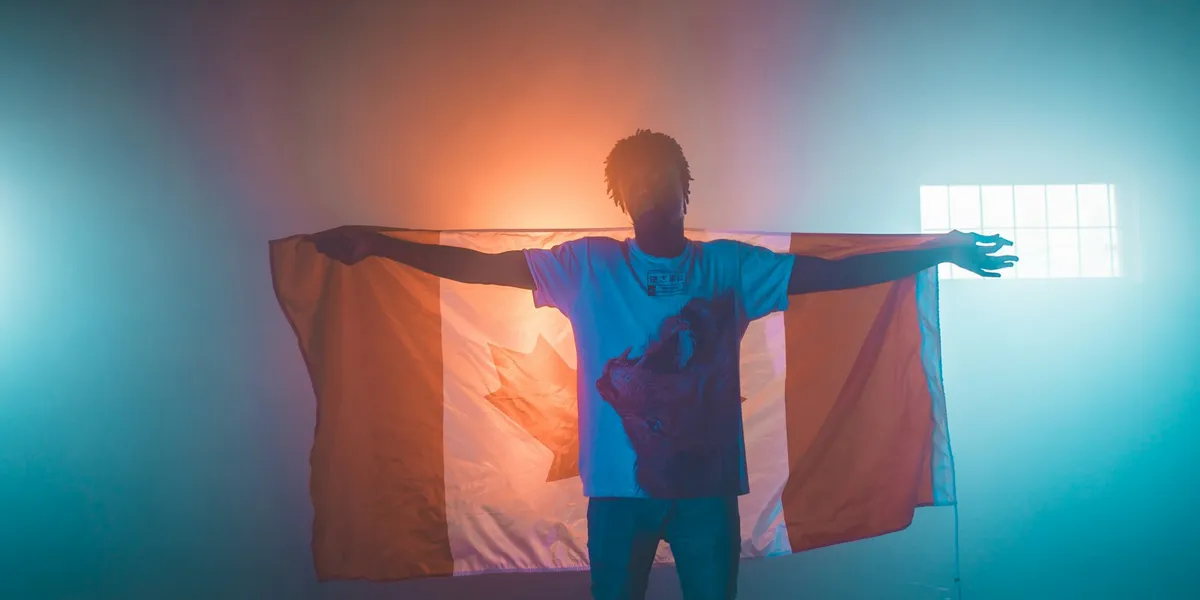 Young African man holding a Canadian flag open behind him