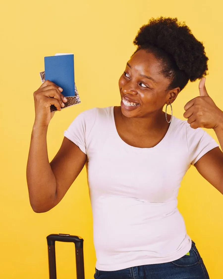 Happy African woman holding up her passport, ready to travel